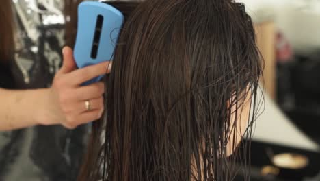 en el salón de belleza y salud, las manos femeninas del maestro peinan el cabello después de teñirlo