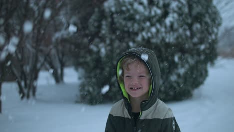 young happy, smiling boy playing in the snow throwing snowflakes in the air in slow motion