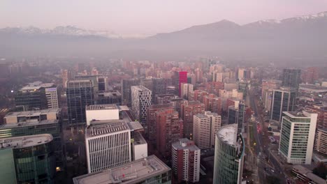 pan left aerial view of the buildings of the municipality of las condes, with the mountain range in the background on a smoggy afternoon, santiago, chile