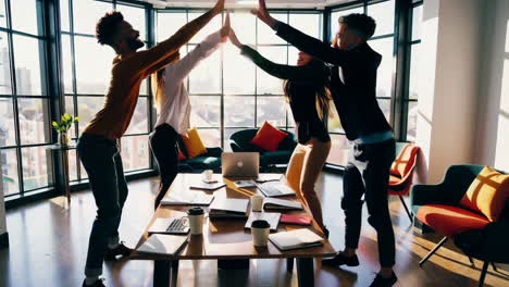 diverse business team celebrating success with high fives in a modern office