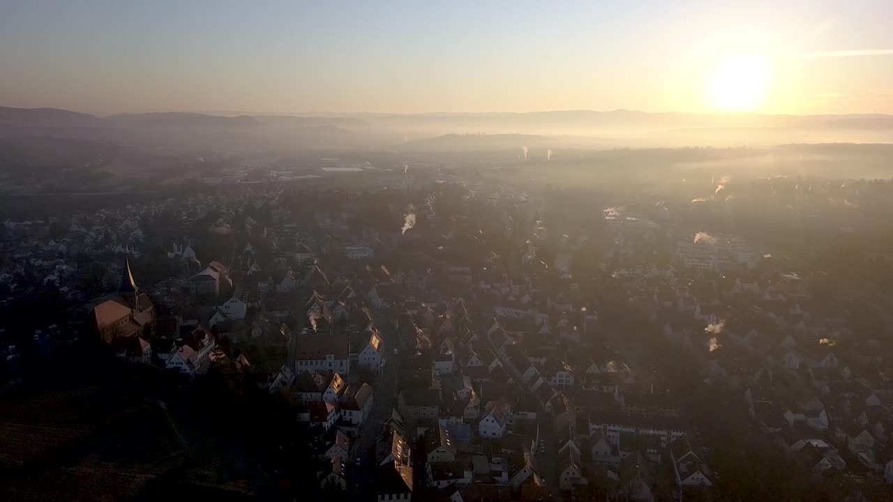 Fly over picturesque Weinsberg town, in Baden Wuerttemberg, during foggy sunset.