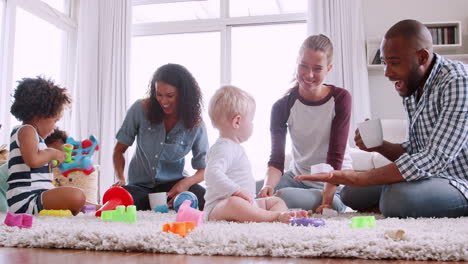 Freunde-Spielen-Mit-Kleinkindern-Auf-Dem-Boden-Und-Trinken-Kaffee