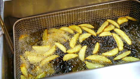 Potato in hot oil. Deep fryer cooking french fries in fast food restaurant. Tasty dish frying in boiling oil. Junk food concept.