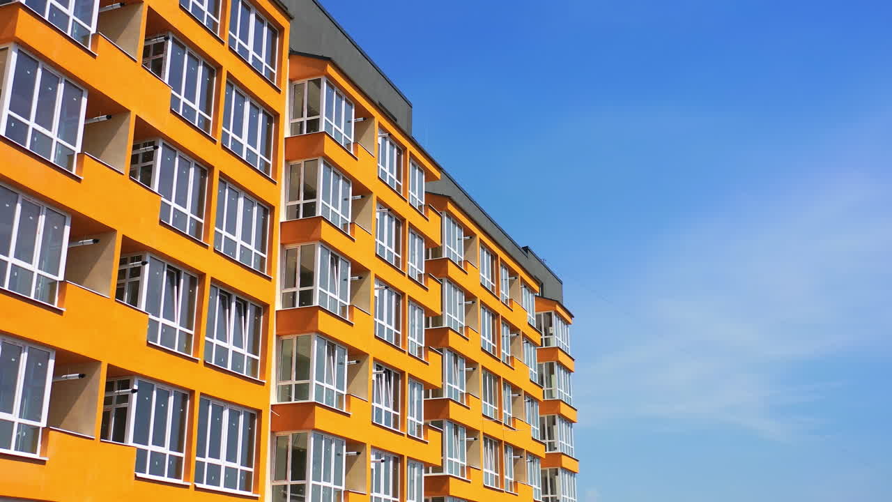 Block of flats with large balconies. Facade of a new high rise building on blue sky backdrop. Bright architecture in the city. Modern multi storey house.