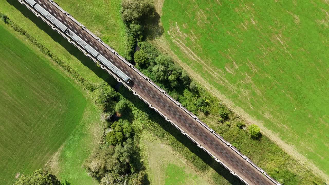 Aerial bird’s-eye view of Viaduct. From directly above, a train glides across the bridge surrounded by lush countryside
