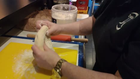 Las-Manos-De-La-Trabajadora-Con-Reloj-Dorado-Amasando-Masa-Con-Harina-De-Trigo-Para-Preparar-Pan-En-El-Horno-En-Su-área-De-Trabajo,-Tiro-Bloqueado,-Pedidos,-Galicia,-España