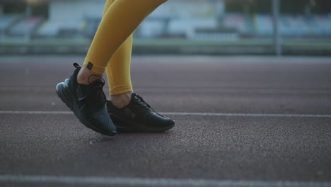 mujer corriendo en una pista al aire libre con ropa deportiva amarilla