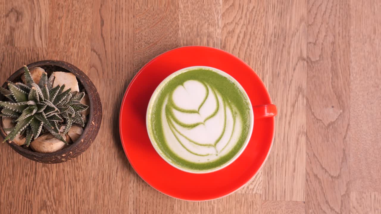 matcha latte con arte de espuma en una mesa de madera