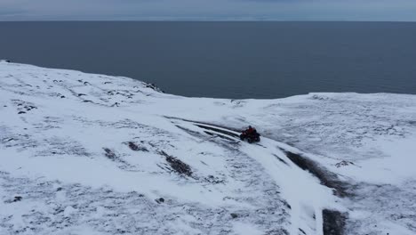 adventurer on quad bike reaching njarðvík coastline during winter, aerial