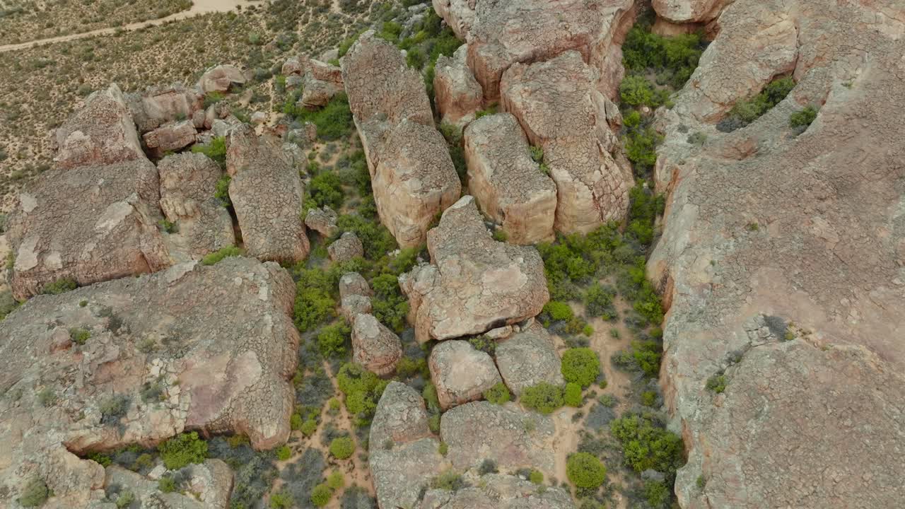 el dron vuela a vista de pájaro sobre el paisaje desértico y las formaciones rocosas en el área desértica de cederberg en sudáfrica sobre una carretera vacía en el desierto - el dron gira ligeramente hacia arriba