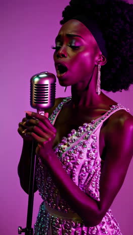 singer performing with a vintage microphone under vibrant purple and pink lighting