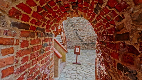 dolly under arched brick walkway leading to open staircase of bauska castle latvia