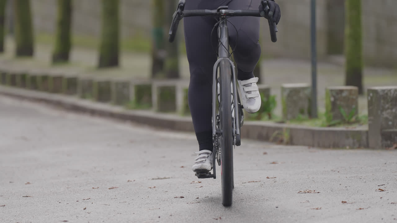 Nærbillede af cyklist, der træder i pedalerne på en cykel på en asfalteret vej.