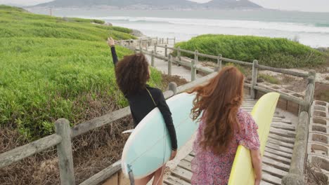 diversas amigas felices yendo a la playa con tablas de surf