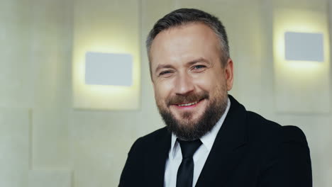 close-up view young caucasian bearded businessman in formal clothes on a podium looking at the camera and smiling in a meeting room