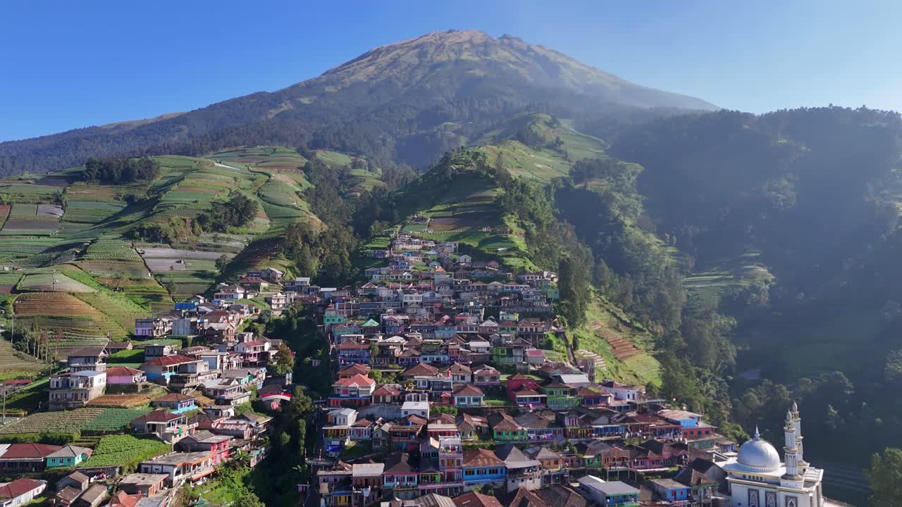 Vista aerea da drone di un colorato villaggio immerso negli altopiani, circondato da terreni agricoli terrazzati e da uno spettacolare paesaggio montano. Tranquilla vita rurale in armonia con la natura. Nepal Van Java, Indonesia