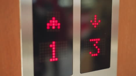 camera inside an elevator. the focus is on the elevator display panel showing red numbers indicating floors one and three