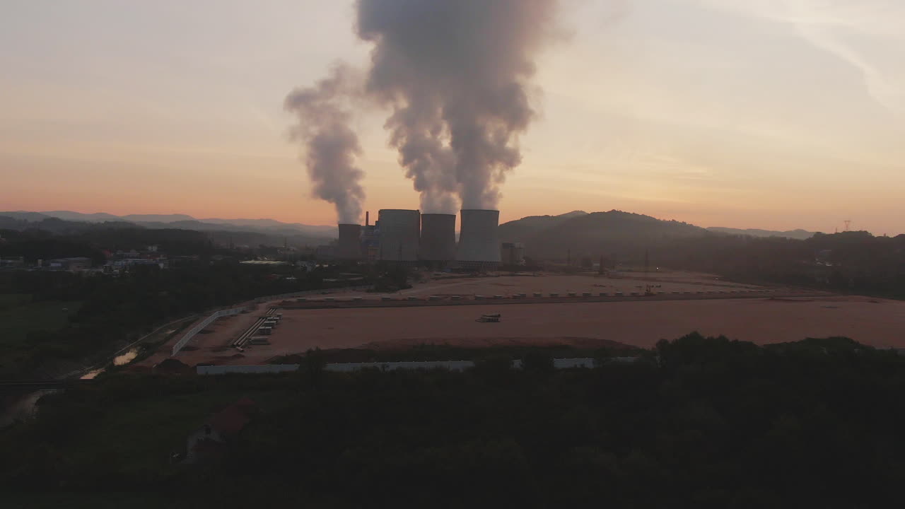 Aerial view of a power plant emitting smoke at sunset