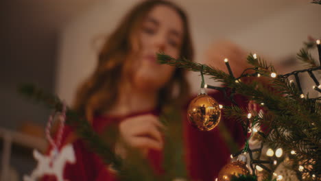 mujer atando bauble mientras decora el árbol de navidad