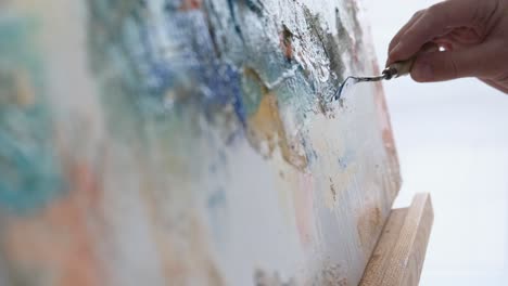 a young male artist works in a studio he uses bright paint on a large white canvas - a young male artist works in a studio, he uses bright paint on a large white canvas. a modern and successful masterpiece of drawing by an artist of abstract art