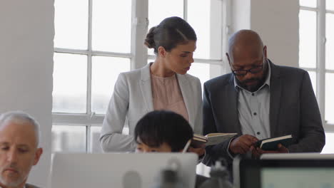 multiracial-business-people-in-boardroom-meeting-attending-corporate-seminar-taking-notes-using-tablet-computer-working-together-in-workplace