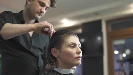 young woman getting her hair dressed in hair salon. stylist-hairdresser at work. man hairdresser brushing hair in beauty salon