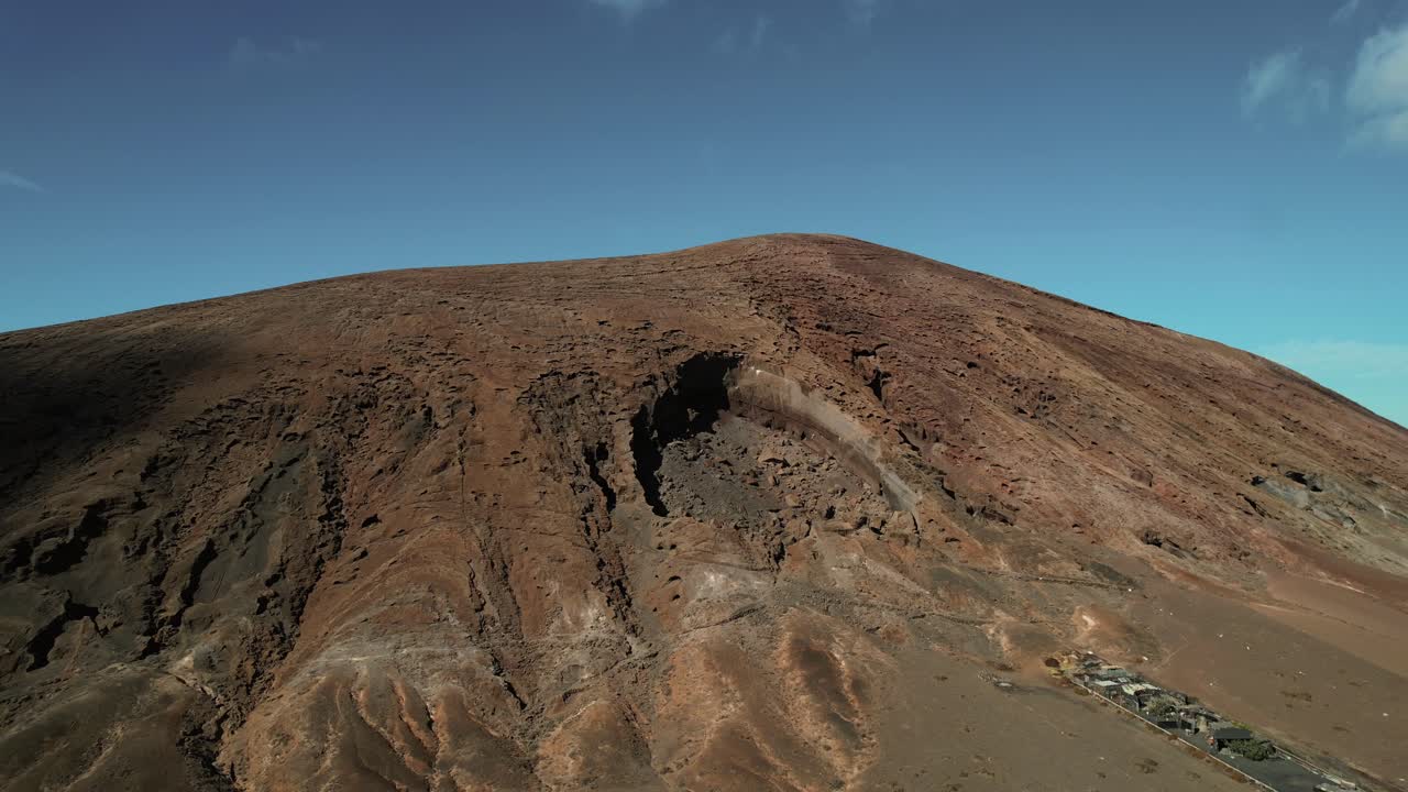 Riprese aeree con drone di terreno vulcanico aspro sotto un cielo azzurro e limpido.