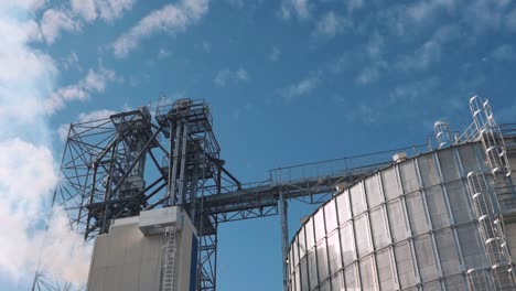large metal hangar for grain. smoke from the elevator dryer. silo with grain