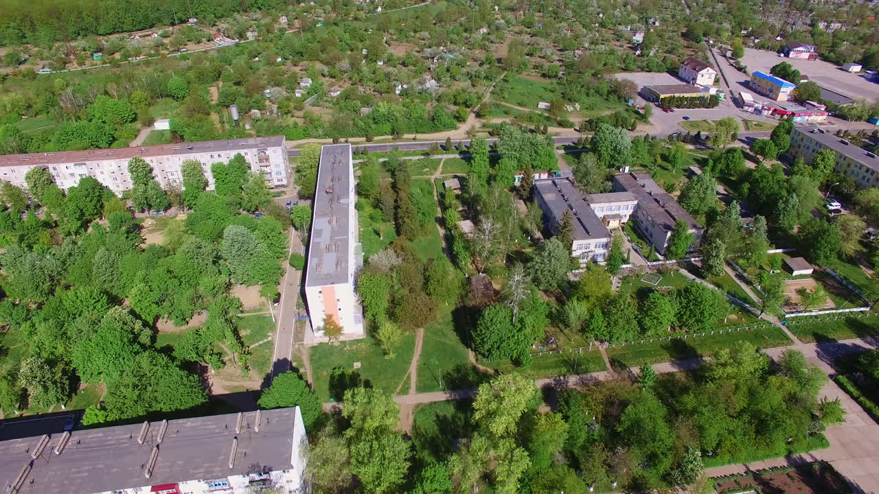 Green sunny city with lots of blocks of flats and cottages. Beautiful river at backdrop separating the city from farmlands.