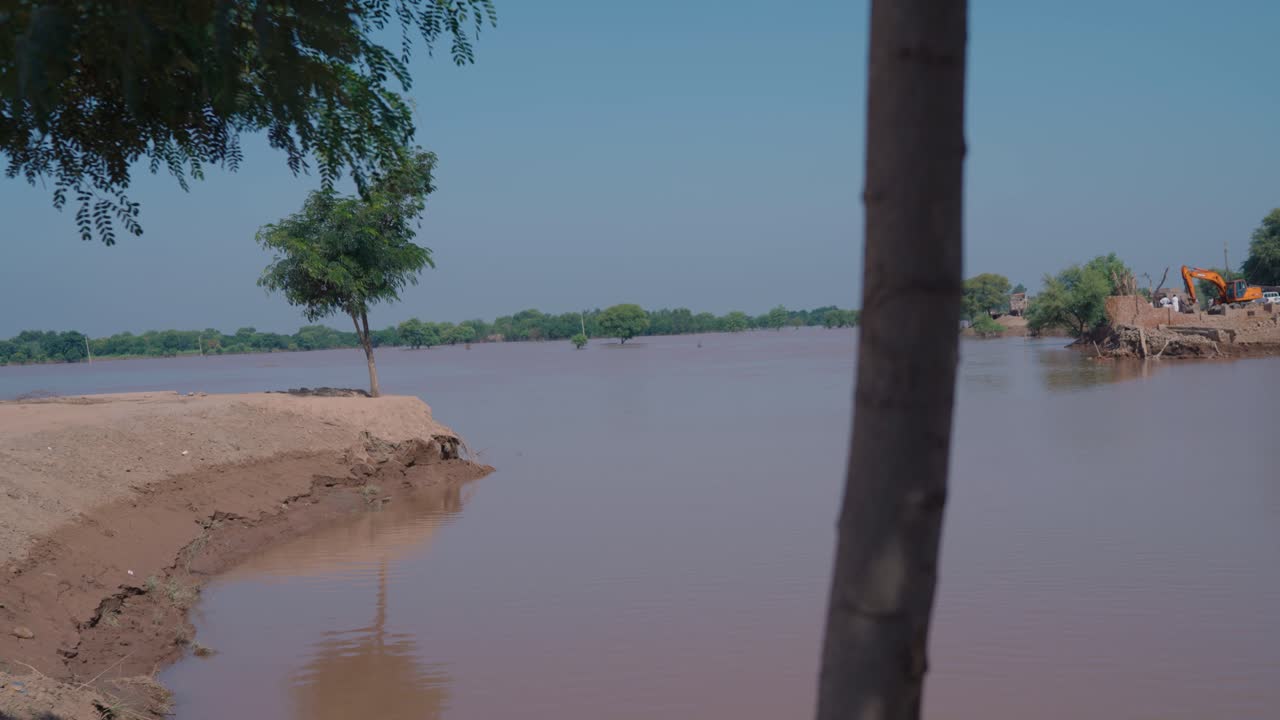 flooded riverbank with machinery working in Jalalpur Pirwala Punjab after heavy rains