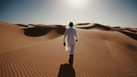 man walking through desert dunes