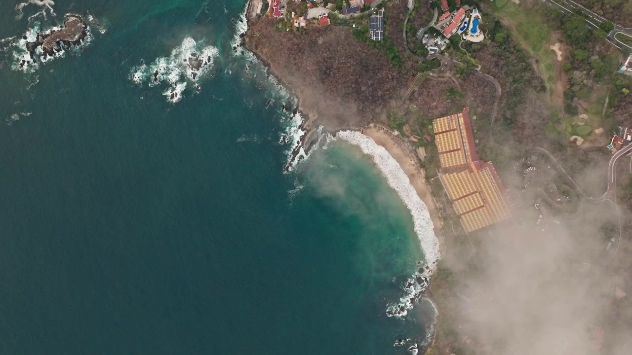 Sfondo aereo di una caletta appartata e di un resort costiero accanto alle acque dell'oceano, drone che crea lo sfondo attraverso le nuvole