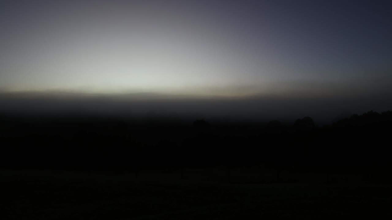 el lapso de tiempo del amanecer dispersando la niebla sobre los campos