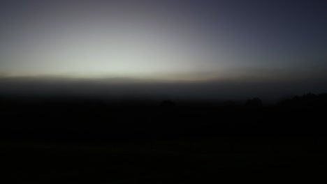 timelapse of sunrise dispersing fog over fields