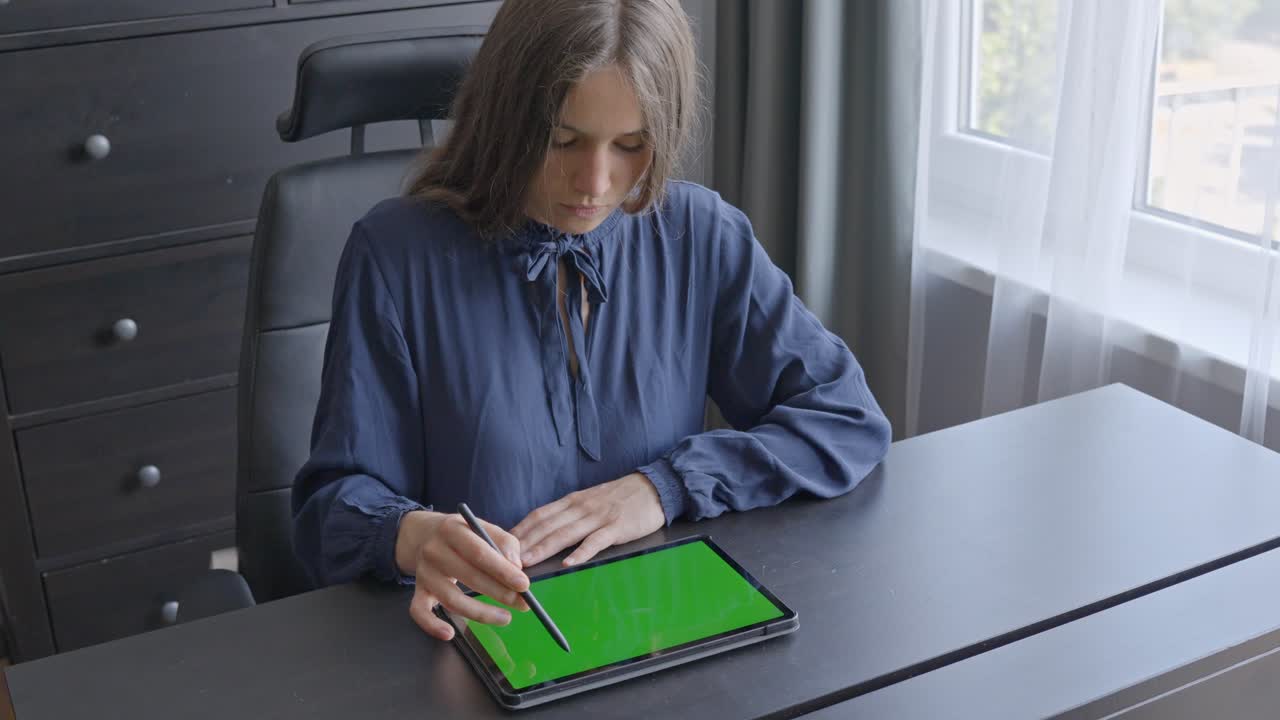 mujer de negocios enfocada trabajando en su mesa de oficina con una tableta de pantalla verde