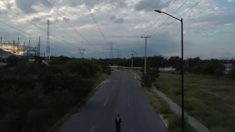 guy going in the middle of electric towers in his bike in a lonely street in a beautifull day
