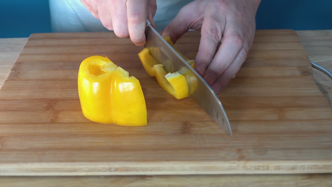 chef masculino cortando un pimiento amarillo fresco
