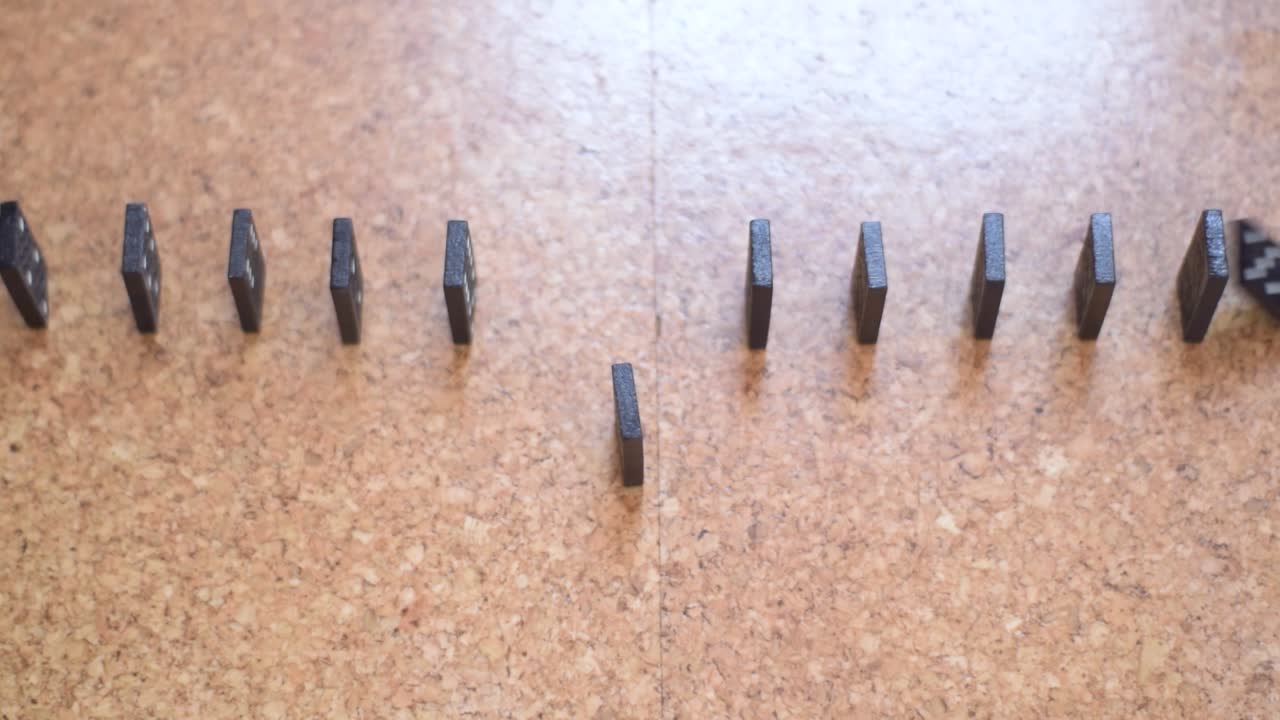 Close up of falling queue of Dominos which symbolize the effect of social distancing. Slow Motion.