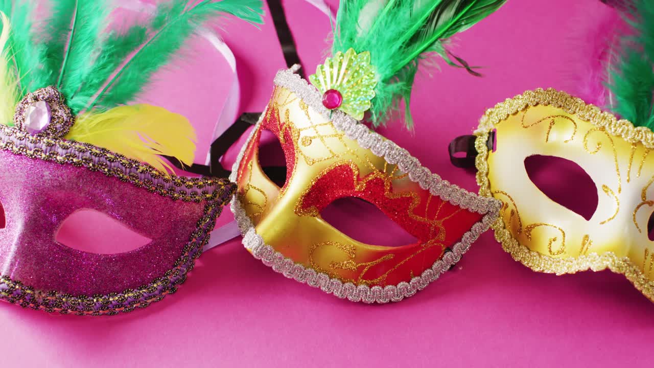 Video di tre maschere di carnevale con piume verdi su sfondo rosa