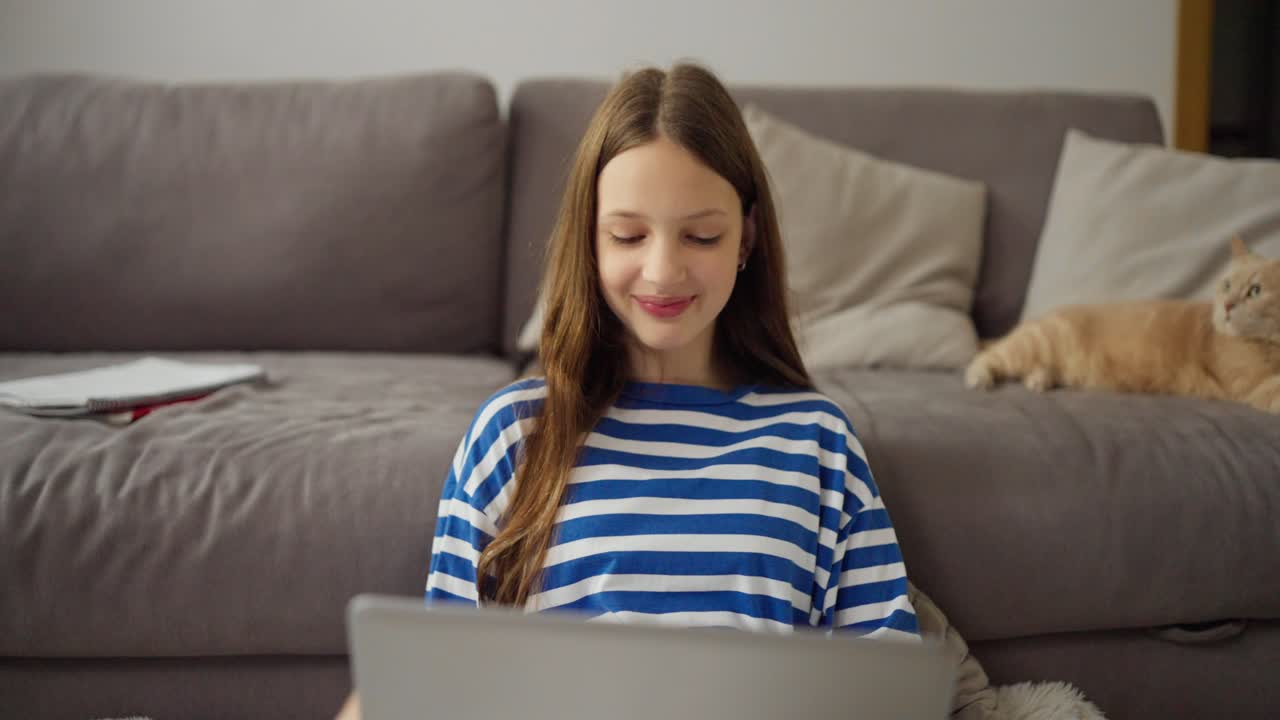 Teenager using laptop at home with a cat