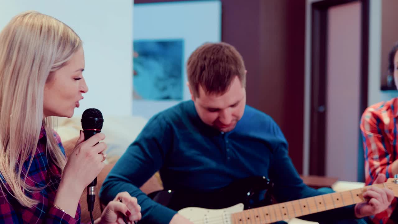 회사 재는 친구들이 마이크로 노래하고 전기 기타를 연주하고, 노래하고 집에서 재미를 느끼고 있습니다.