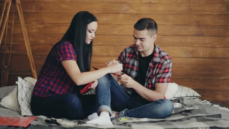 a loving couple are sitting on a bed and carving hearts with scissors to valentine's day