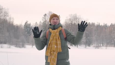 vista frontal de un hombre con ropa de invierno jugando a tirar nieve en un bosque nevado