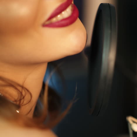 young woman recording a song in a professional studio. profile of a woman with a beautiful face and red lips square video