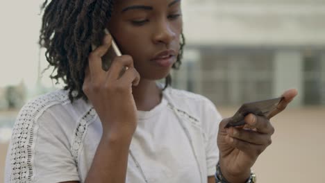 Focused-young-woman-talking-on-phone-and-holding-credit-card.