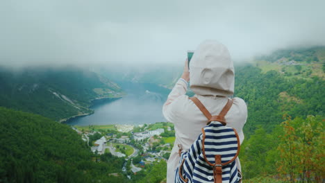 女性旅行者は、ノルウェーのフィヨルドの美しい景色を写真に撮ります スカンジナビアへの旅行