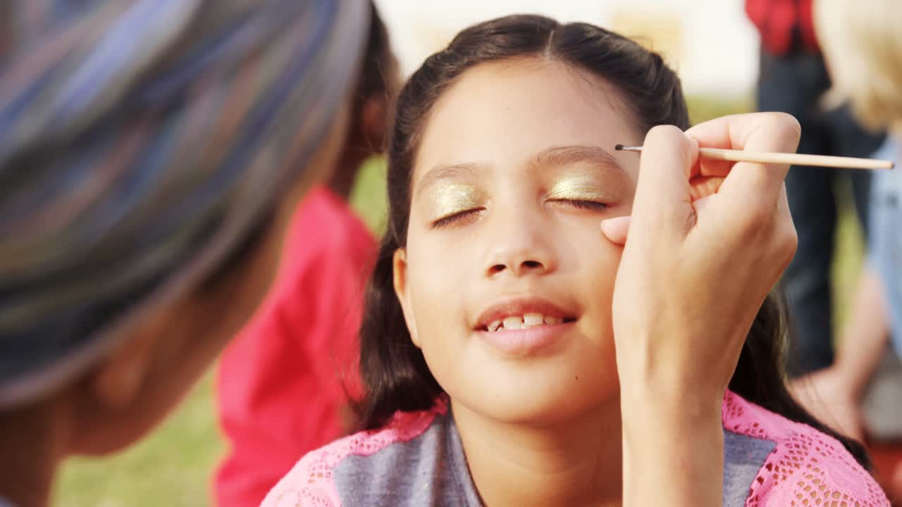 mujer aplicando pintura en las cejas de la niña 4k