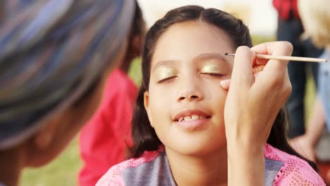 woman applying paint on girl eyebrows 4k