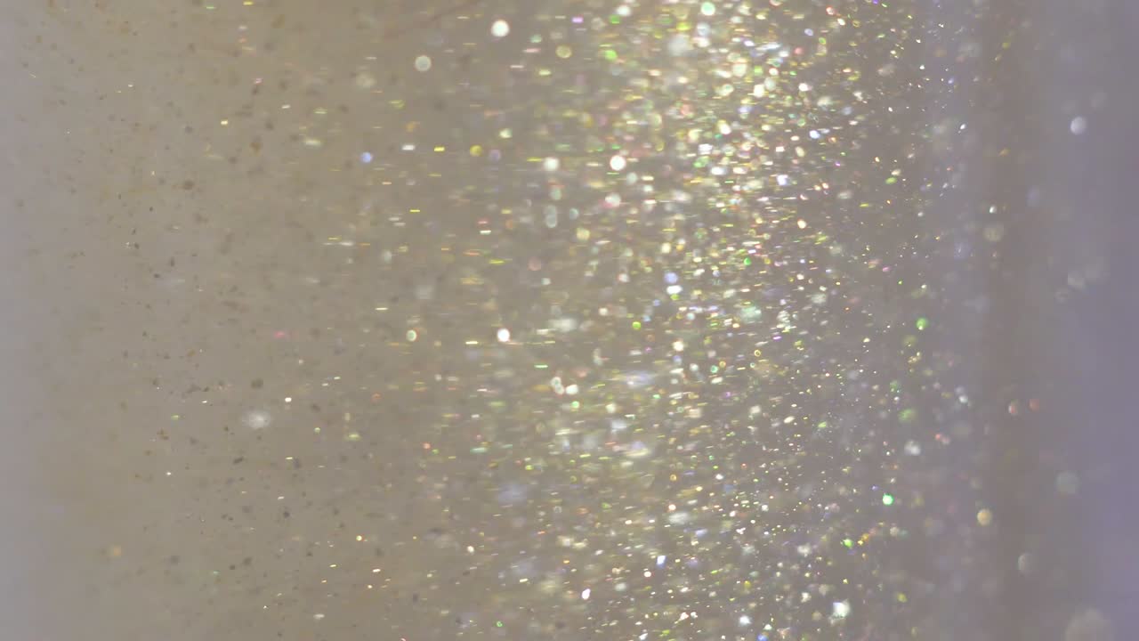primer plano de brillo flotando en el vodka. pintura dorada de colores mezclándose en el agua. tinta girando bajo el agua. nube de tinta sedosa. vista macro