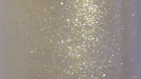 close-up of glitter floating in vodka. colorful gold paint mixing in water. ink swirling underwater. cloud of silky ink. macro view